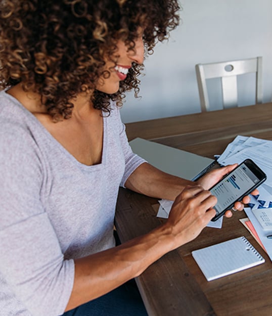 Woman sitting at home managing bank account and finances through a mobile app